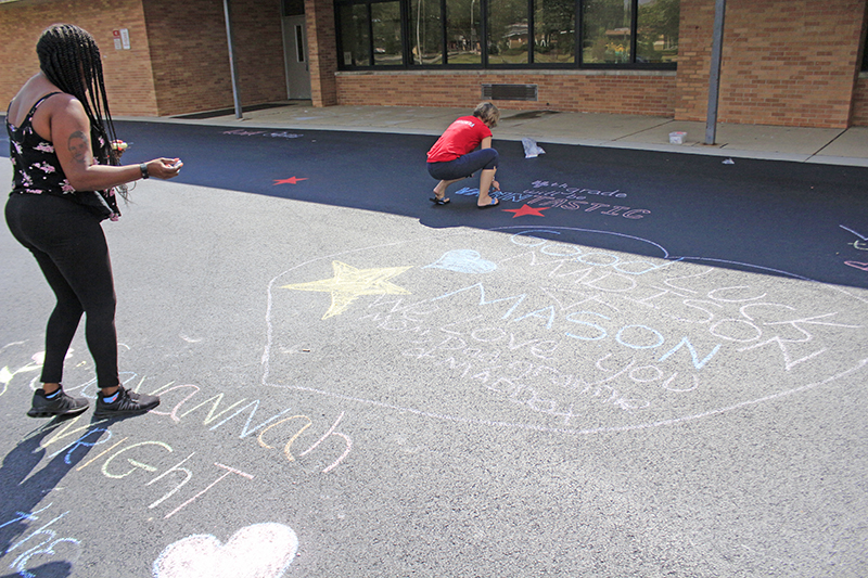 Ebonie Hall steps back to check her chalk greeting for her twins, Madison and Mason, to see on their first day of fourth grade.